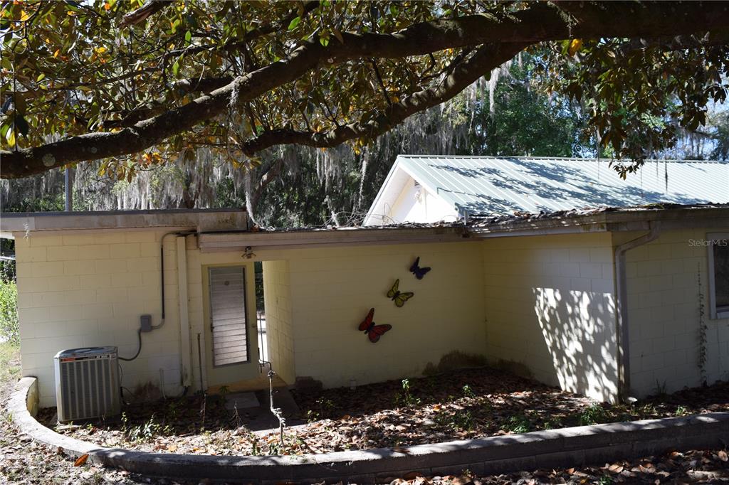 An exterior view of a light-colored concrete block house with three decorative butterflies on the wall — 121 AWEEMA WAY, MELROSE, FL