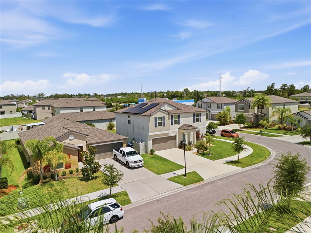 An aerial view shows two suburban houses with driveways, lawns, and solar panels on one roof — 5052 WHITE CHICORY DRIVE, APOLLO BEACH, FL