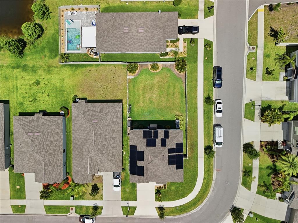 An aerial view shows suburban houses with solar panels, swimming pools, and driveways — 5052 WHITE CHICORY DRIVE, APOLLO BEACH, FL