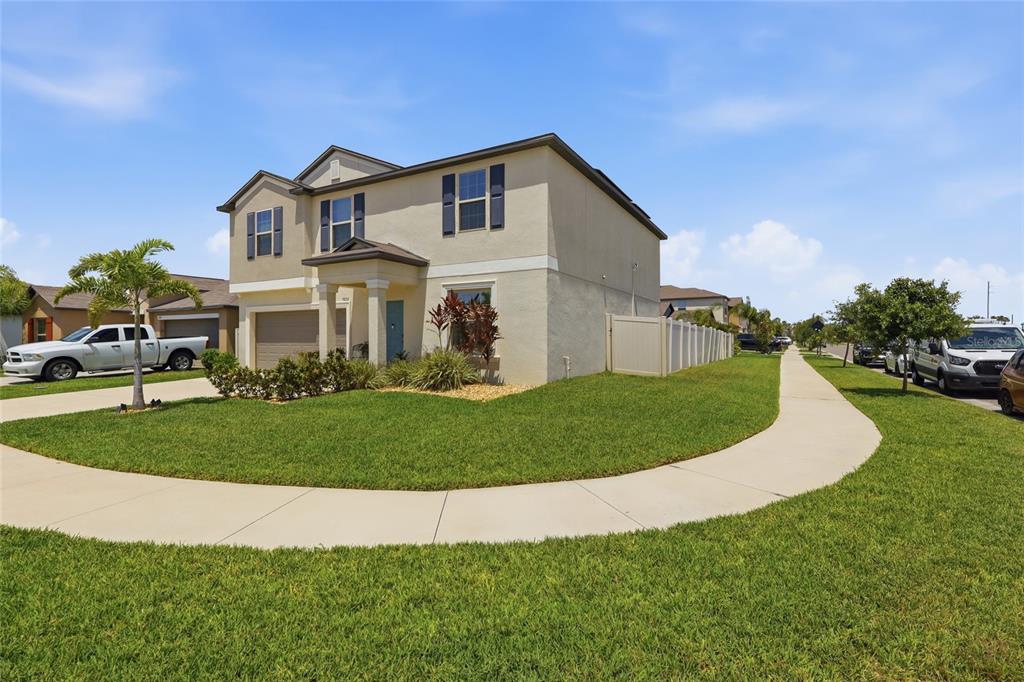 A two-story suburban house with a tan stucco exterior and a front-facing garage — 5052 WHITE CHICORY DRIVE, APOLLO BEACH, FL