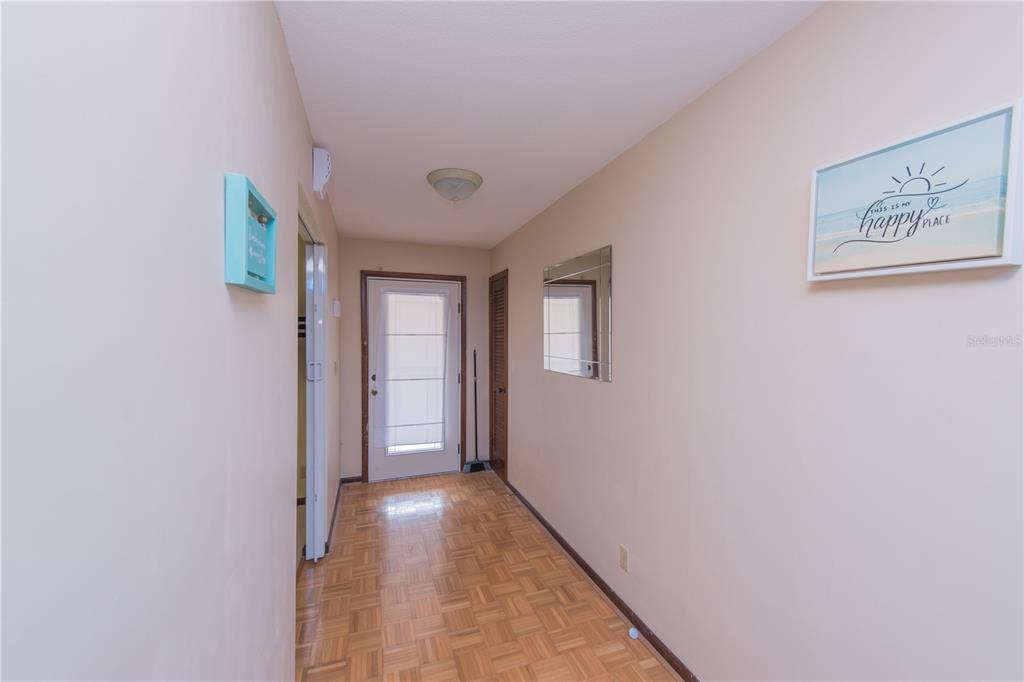 A hallway features light-colored walls, parquet wood flooring, a front door, and wall decor — 34 OAKMONT CIRCLE, ORMOND BEACH, FL