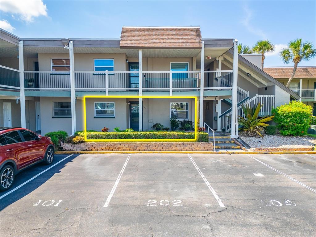 A two-story apartment building exterior features a ground-floor unit highlighted by a yellow box — 1028 APOLLO BEACH BOULEVARD UNIT 104, APOLLO BEACH, FL