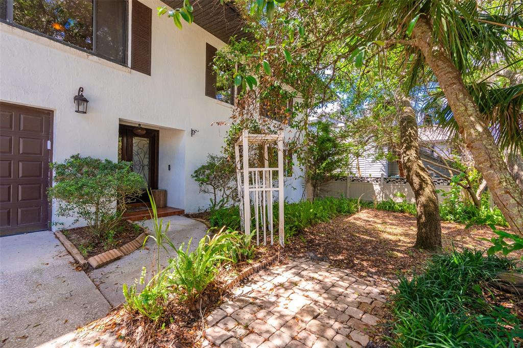 A wide, open-concept garage with concrete floors, metal shelving, and a rear exit to stairs — 40 CONCORD DRIVE, ORMOND BEACH, FL