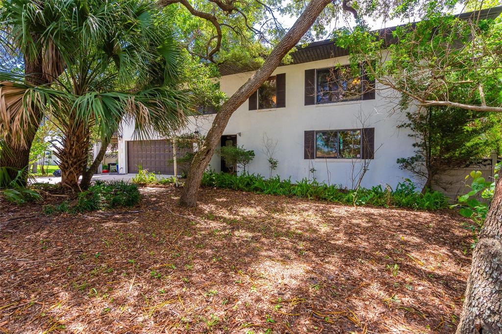 A wide, open garage with concrete flooring, storage shelving, and a rear roll-up door — 40 CONCORD DRIVE, ORMOND BEACH, FL