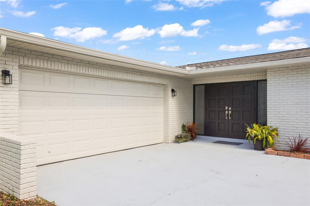 A white brick house exterior features a two-car garage and dark double front doors — 13635 97TH TERRACE, SEMINOLE, FL