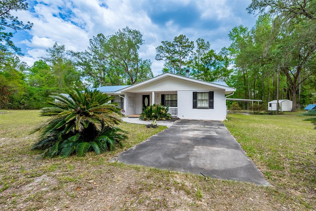 A single-story white house with a metal roof sits on a large, grassy lot — 1753 SE HIGHWAY 349, OLD TOWN, FL