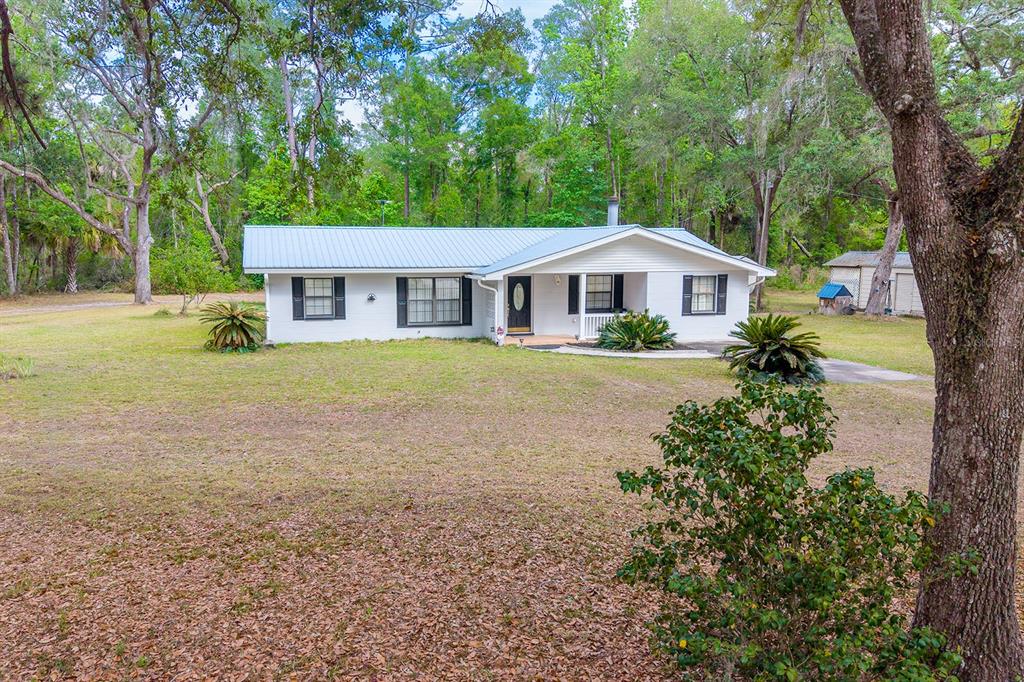 A single-story white house with a metal roof sits on a large, grassy lot — 1753 SE HIGHWAY 349, OLD TOWN, FL