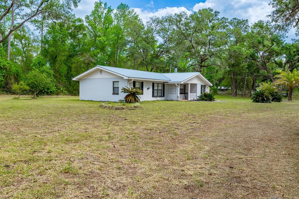 A white, single-story house with a concrete driveway and a large cycad in the yard — 1753 SE HIGHWAY 349, OLD TOWN, FL