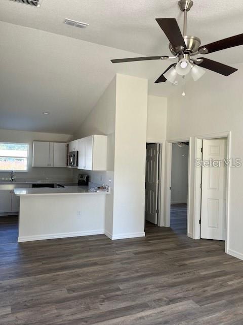 An open-concept kitchen features white cabinets, a breakfast bar, and wood-look flooring — 3783 SE 140TH LANE, SUMMERFIELD, FL