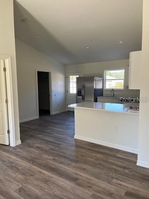 A kitchen with white cabinets, stainless steel appliances, and wood-look flooring opens to a hallway — 3783 SE 140TH LANE, SUMMERFIELD, FL