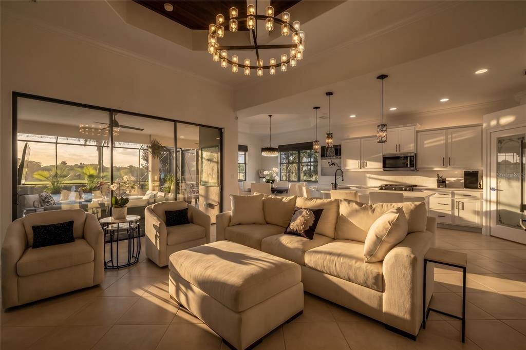 A bright open-concept living room and kitchen with tile floors, a large chandelier, and patio — 189 ASPEN WAY, PALM COAST, FL