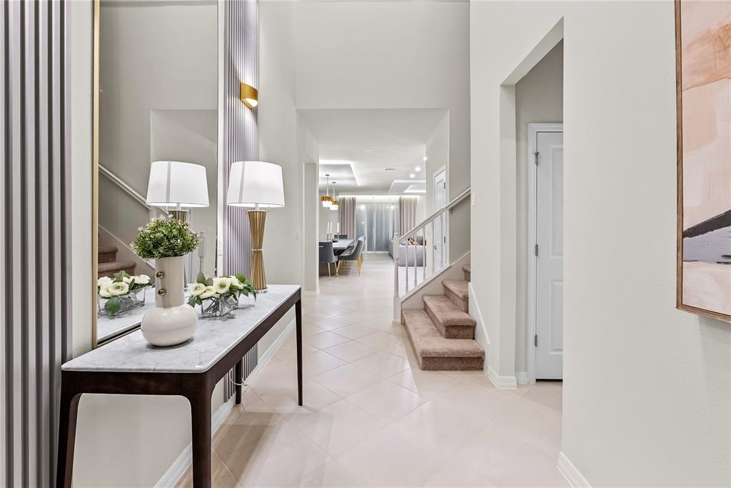 A bright entryway features a marble-topped console table, a large mirror, and carpeted stairs — 15961 CAPE CORAL LOOP, CLERMONT, FL