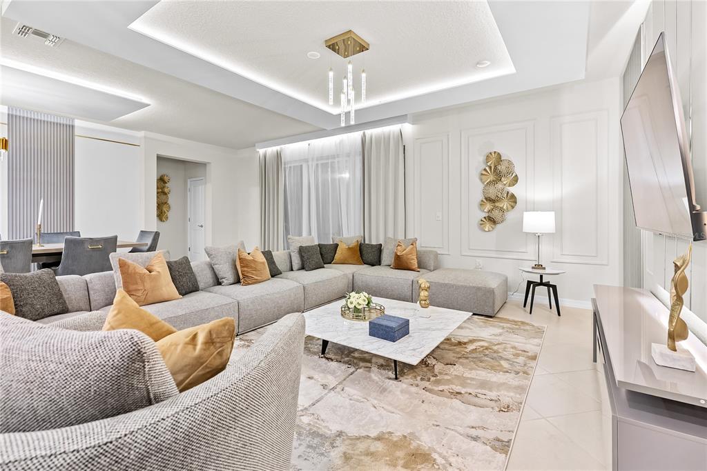 A modern living room features a large gray sectional sofa, marble coffee table, and chandelier — 15961 CAPE CORAL LOOP, CLERMONT, FL
