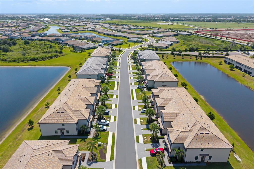 A two-story townhouse exterior features a gray garage door, a paved driveway, and an American flag — 15210 SUNNY DAY DRIVE, BRADENTON, FL