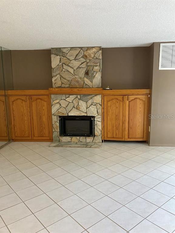 A room features a stone fireplace flanked by built-in wooden cabinets and tiled flooring — 5980 80TH STREET N UNIT 205, ST PETERSBURG, FL