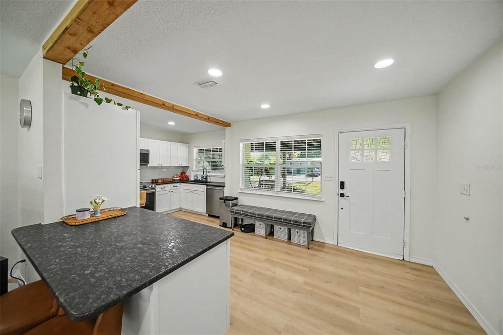 A kitchen features white cabinetry, stainless steel appliances, dark countertops, and light wood flooring — 4636 W BAY COURT AVENUE, TAMPA, FL