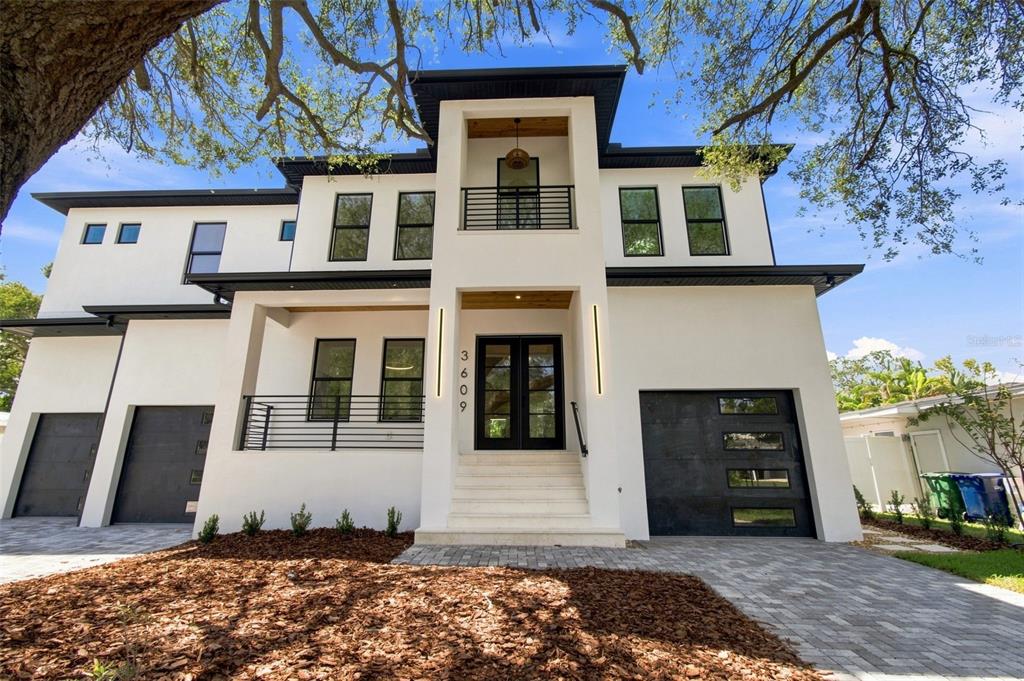 A modern two-story white house with black trim, a balcony, and a multi-car garage — 3609 S GARDENIA AVENUE, TAMPA, FL