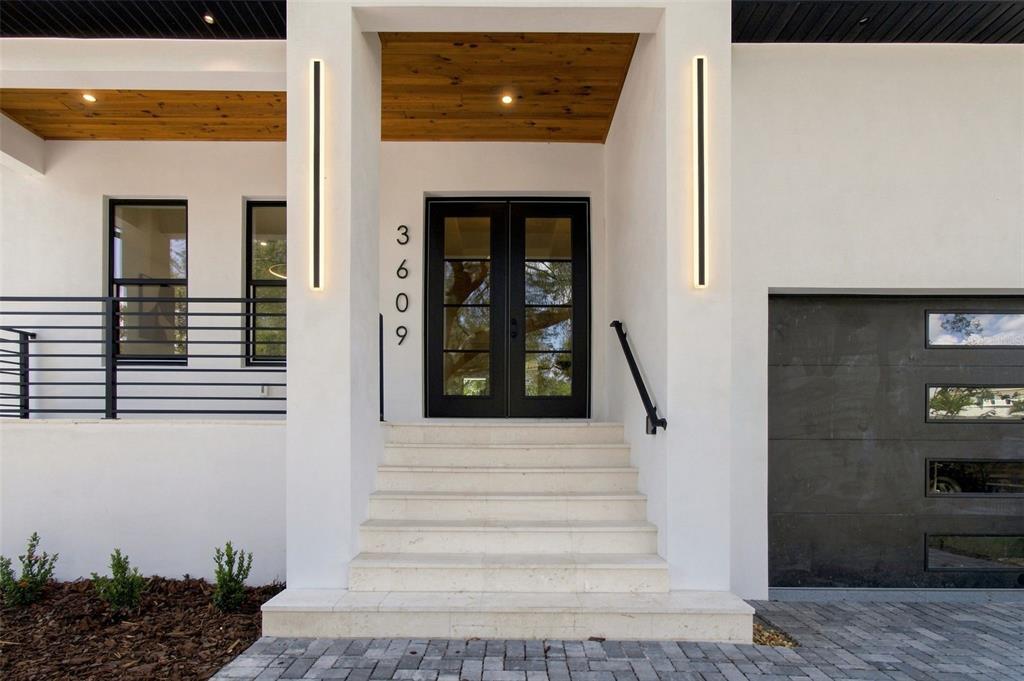 The exterior of a modern home features a double front door, stone steps, and lighting — 3609 S GARDENIA AVENUE, TAMPA, FL