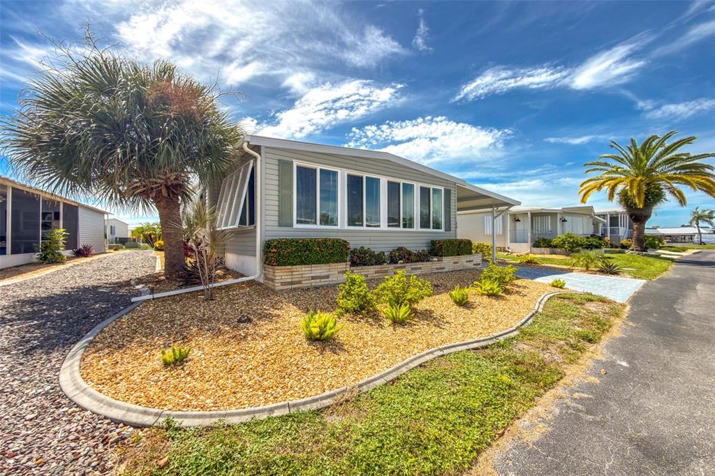 A light gray manufactured home features a gravel yard, palm trees, and a concrete driveway — 13 S MARINA PLAZA, ENGLEWOOD, FL