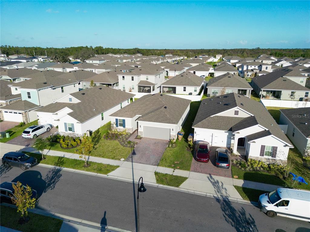 An aerial view shows a suburban street with modern single-family homes and parked vehicles — 1177 FOX HEDGE LANE, ST CLOUD, FL