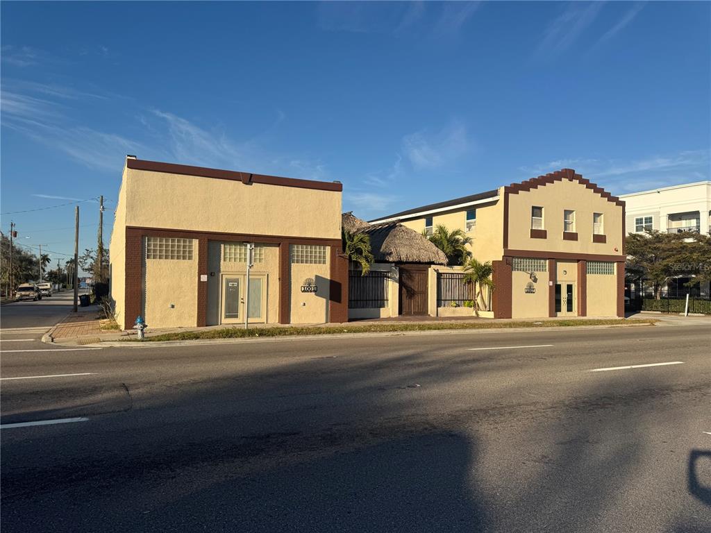 Two adjacent commercial buildings with stucco facades and glass block windows stand along a street — 1001 MANATEE AVENUE E, BRADENTON, FL