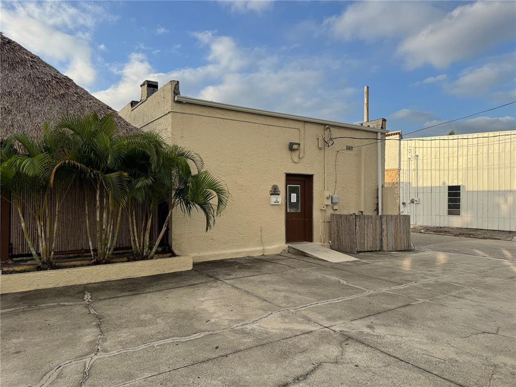The exterior of a beige commercial building features a brown door and a palm tree — 1001 MANATEE AVENUE E, BRADENTON, FL