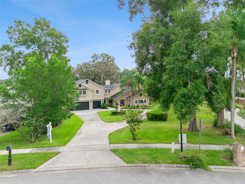 A two-story house with a beige exterior, black garage doors, and a circular garden statue — 4574 SAILBREEZE COURT, ORLANDO, FL