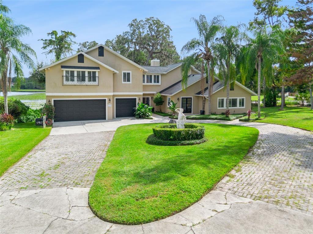 A covered patio features a brick paver floor, two wicker chairs, and a decorative metal gate — 4574 SAILBREEZE COURT, ORLANDO, FL