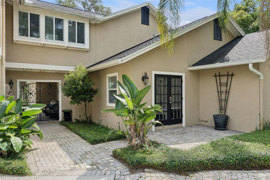 A grassy backyard with mature trees overlooks a lake with lily pads — 4574 SAILBREEZE COURT, ORLANDO, FL