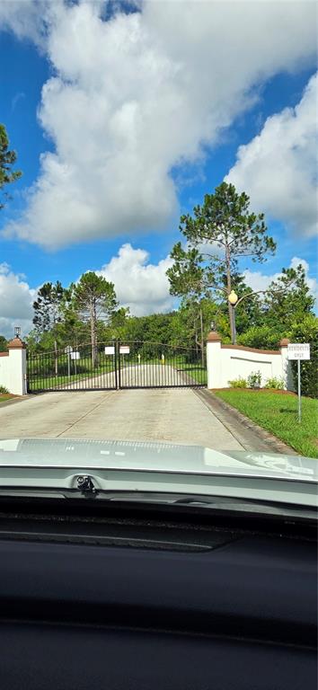 A gated entrance with a white wall and metal fence leads into a residential community — BELLERIVE DRIVE, CLERMONT, FL