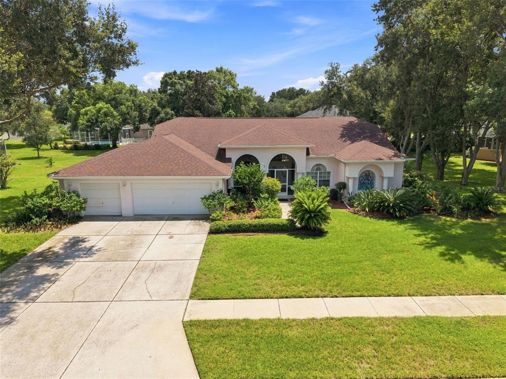 An exterior view of a single-story house with a two-car garage and a large lawn — 1518 FISHING LAKE DRIVE, ODESSA, FL