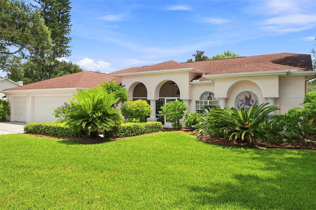 A single-story house with a brown roof, arched entryway, and landscaped front yard — 1518 FISHING LAKE DRIVE, ODESSA, FL