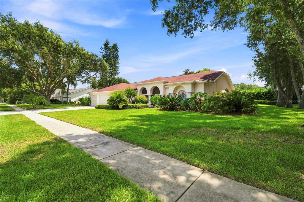 A single-story house with a red roof, arched entryway, and a large front lawn — 1518 FISHING LAKE DRIVE, ODESSA, FL