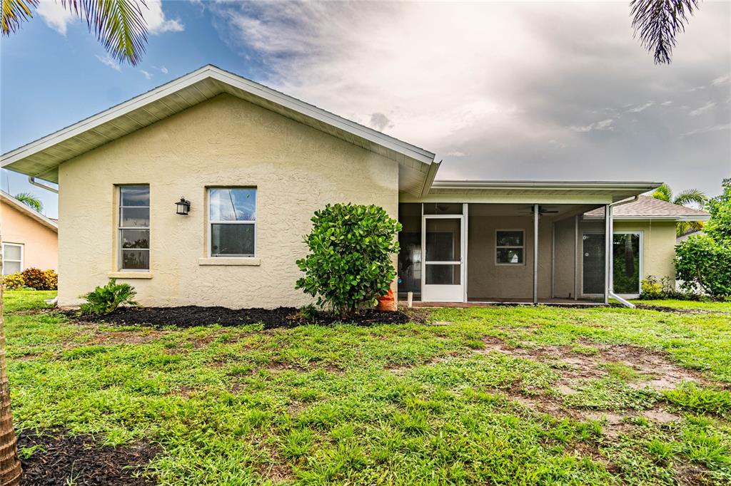 The exterior of a beige house features a screened-in patio and a grassy backyard — 1501 63RD STREET W, BRADENTON, FL