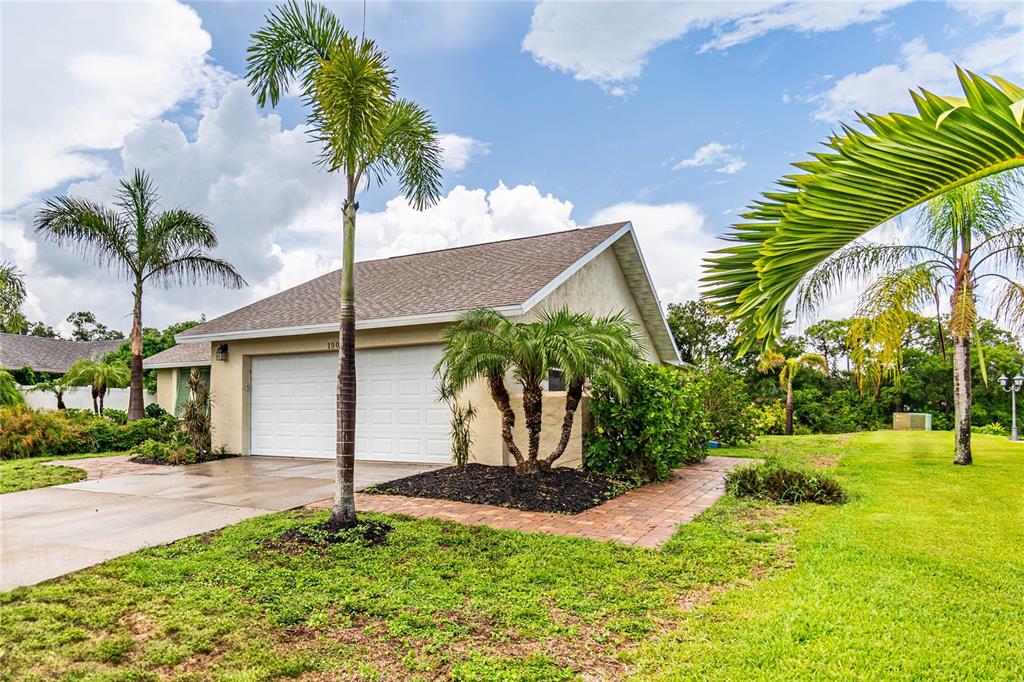 A beige house with a two-car garage, palm trees, and a brick walkway — 1501 63RD STREET W, BRADENTON, FL