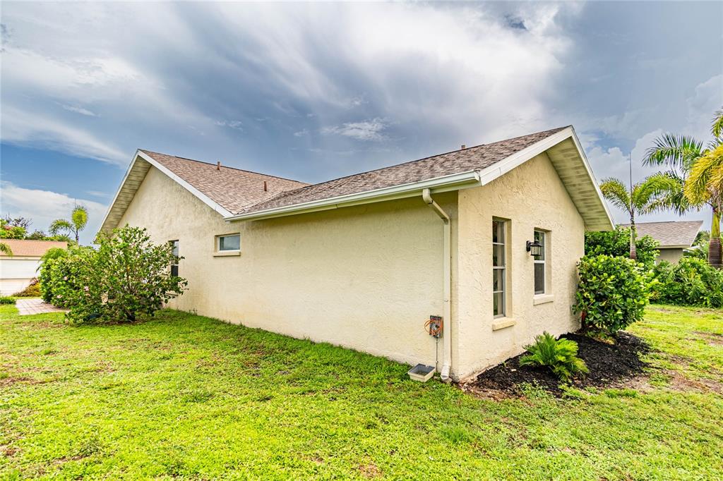 The exterior side view of a beige stucco house with a shingled roof and landscaping — 1501 63RD STREET W, BRADENTON, FL