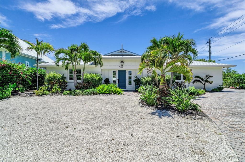 A white single-story house with a blue door and palm trees in the front yard — 501 68TH STREET, HOLMES BEACH, FL