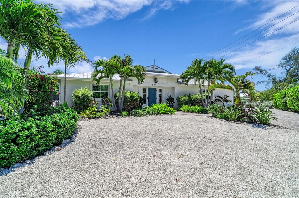 A single-story house with a white exterior, palm trees, and a gravel driveway — 501 68TH STREET, HOLMES BEACH, FL
