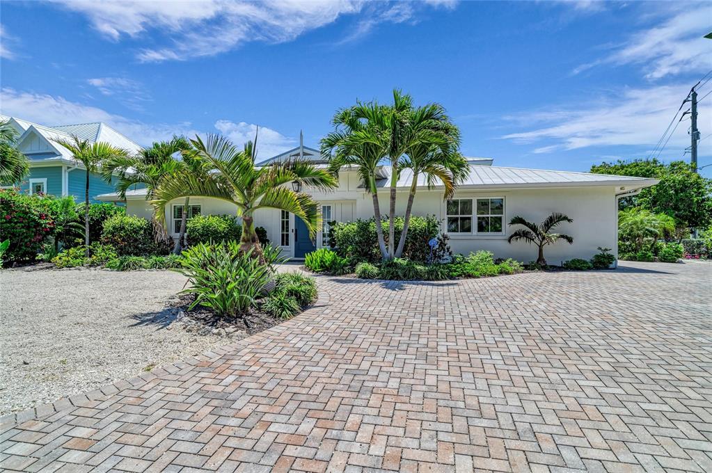 A single-story house with a white exterior, metal roof, and a brick-paved driveway — 501 68TH STREET, HOLMES BEACH, FL