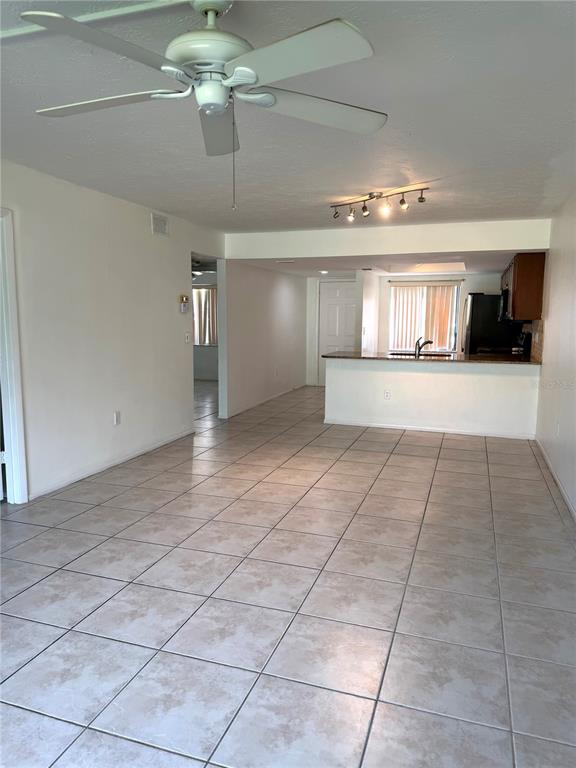 An open-concept living area features light-colored tile flooring, a ceiling fan, and a kitchen island — 7750 EAGLE CREEK DRIVE UNIT 7750, SARASOTA, FL