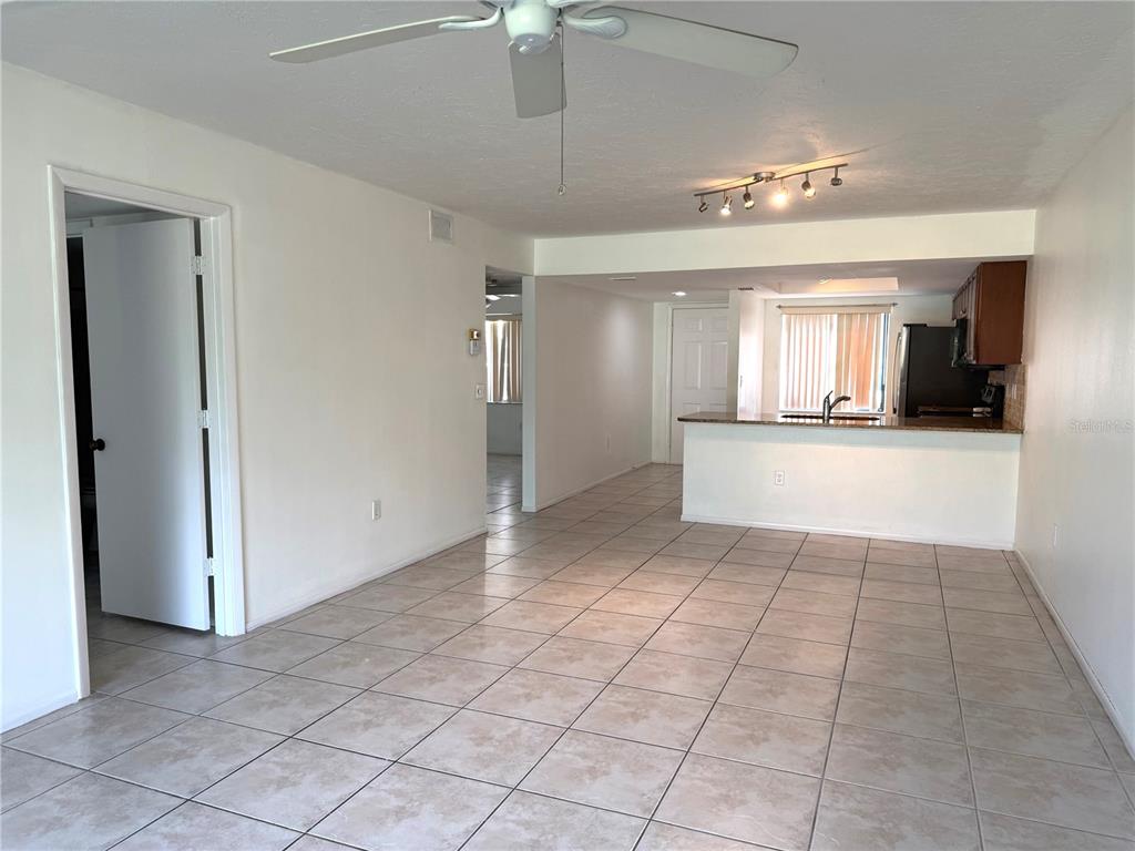 An open-concept living area features light-colored tile flooring, a ceiling fan, and a kitchen counter — 7750 EAGLE CREEK DRIVE UNIT 7750, SARASOTA, FL