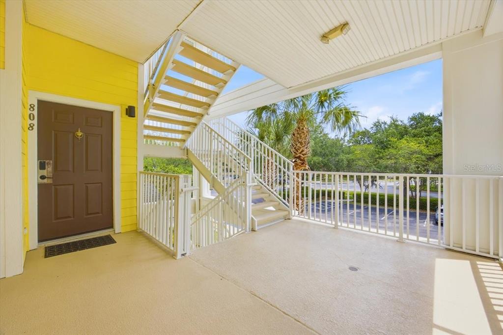 An outdoor landing features a brown front door, yellow siding, and a metal staircase — 808 LUCAYA LOOP, DAVENPORT, FL
