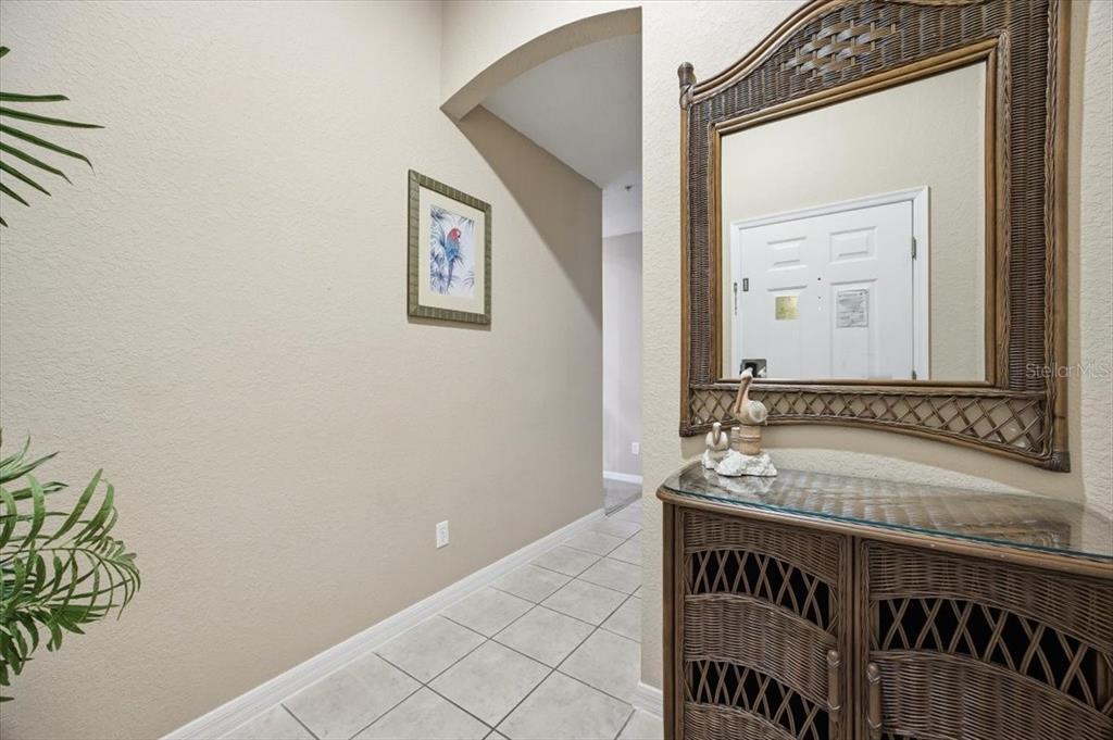 A tiled entryway features a wicker console table, a matching mirror, and a framed parrot print — 808 LUCAYA LOOP, DAVENPORT, FL