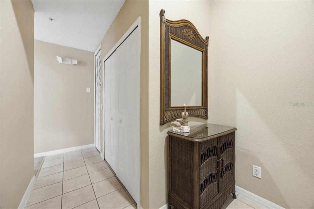A hallway features tile flooring, a white closet door, and a wicker cabinet with a mirror — 808 LUCAYA LOOP, DAVENPORT, FL
