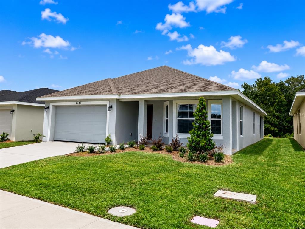 A single-story gray house with a two-car garage and a manicured front lawn — 7642 BENT TREE LOOP, ST CLOUD, FL