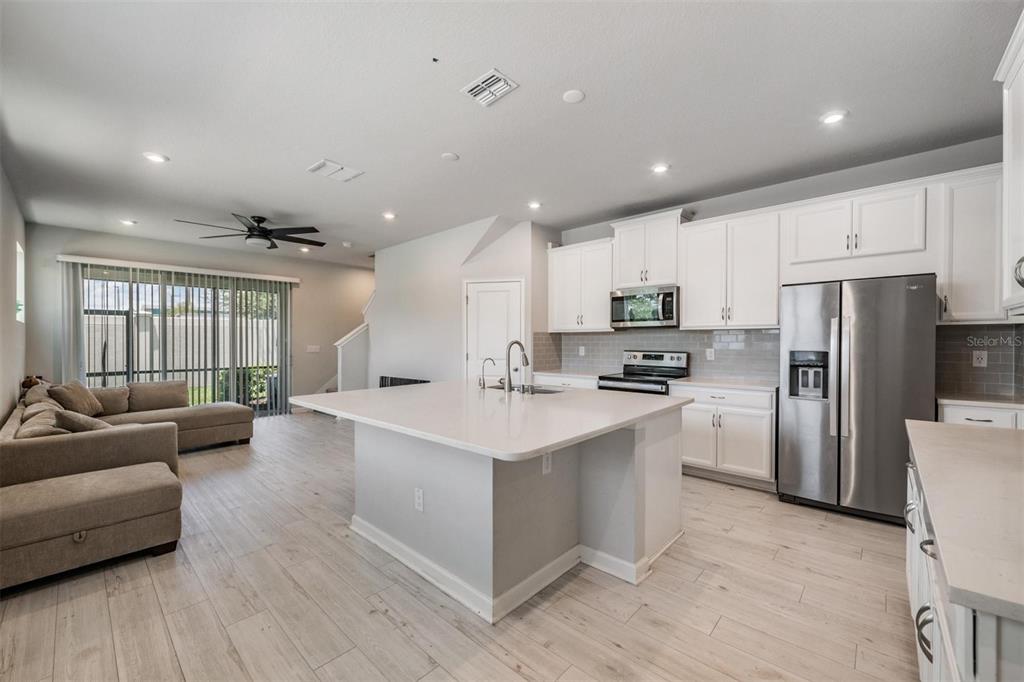 A modern kitchen with white cabinets, a large island, and stainless steel appliances — 19153 ELSIMONT ISLE, LUTZ, FL