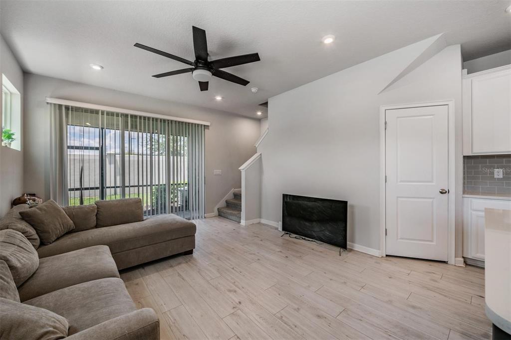 A living room features light wood-look flooring, a sectional sofa, and a sliding glass door — 19153 ELSIMONT ISLE, LUTZ, FL
