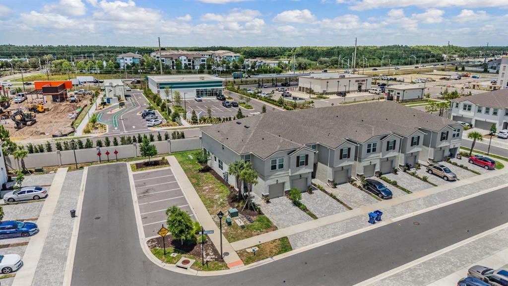 An aerial view shows a row of townhomes with attached garages next to a parking lot — 19153 ELSIMONT ISLE, LUTZ, FL