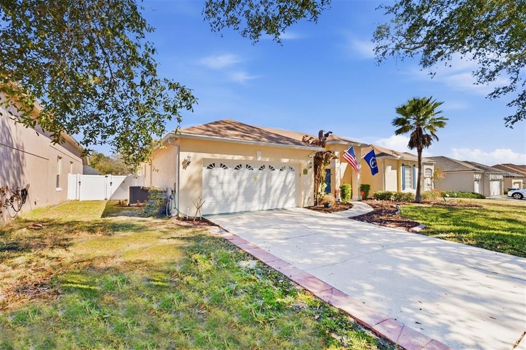 A single-story house with a white garage door, a concrete driveway, and an American flag — 7909 FERNLEAF DRIVE, ORLANDO, FL