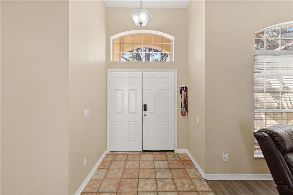 An entryway features double white doors, a transom window, a pendant light, and tiled flooring — 7909 FERNLEAF DRIVE, ORLANDO, FL